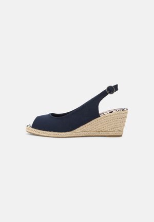 Zapato de cuña espadrille de color azul marino con diseño de punta descubierta, tacón de cuña envuelto en yute y tira trasera ajustable que presenta un anillo de metal.