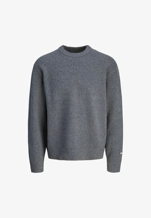 Szary dzianinowy sweter, jasnoniebieskie szerokie dżinsy i beżowe buty. Biały detal logo na mankiecie swetra, na jednolitym tle.