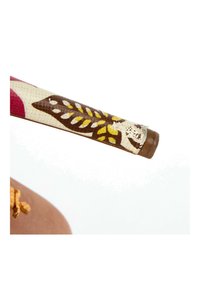 Gros plan d'une branche de lunettes de soleil avec un motif de feuilles marron, jaune et blanc sur tissu et une petite zone usée près de la charnière.