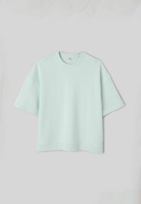 Sweat-shirt oversize vert pastel clair à manches courtes avec col rond, présenté sur un fond gris clair uni.