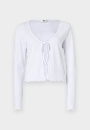 Baltas ryškiai suplanuotas ilgomis rankovėmis kardiganas su giliu V formos iškirpimu, priekinio rišimo detale ir banguotu kraštu. Pagamintas iš minkštos mezgimo medžiagos.