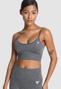 Szara, krótka sportowa biustonosz z cienkimi ramiączkami, teksturowanym materiałem i małym białym logo po lewej stronie. Prosty i dopasowany design.