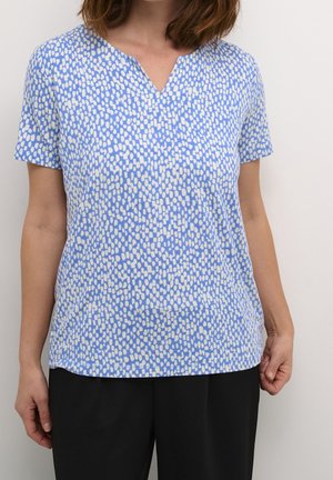 Blaues Kurzarmshirt mit V-Ausschnitt und einem weißen, unregelmäßigen Punktmuster auf dem gesamten Stoff. Weicher Stoff und lockere Passform.