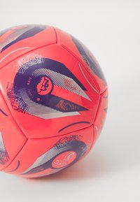 Crvena nogometna lopta s glatkom površinom, grafičkim akcentima u tamnoplavoj i srebrnoj boji te karakterističnim uzorcima; označena logotipom UEFA Europskog prvenstva za žene.