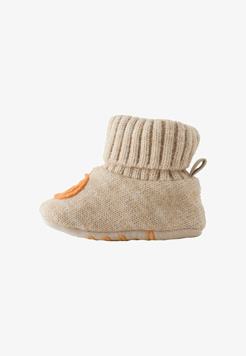 Chausson bébé beige tricoté avec revers plié et détail décoratif orange sur le bout, semelle souple avec points antidérapants, vue de côté sur fond blanc.