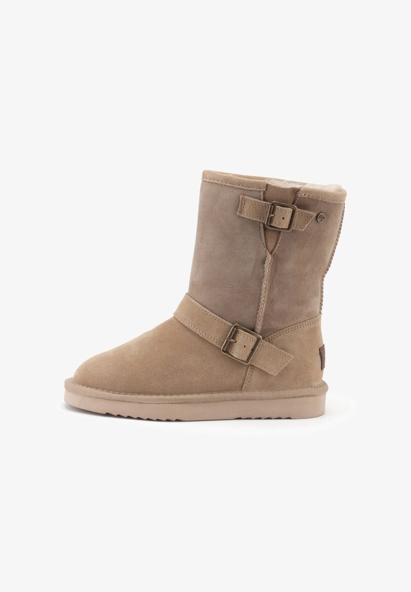 Tan suède enkellaars met een zachte faux-fur voering, verstelbare banden en een platte rubberen zool. Rond toelopend en gestikt detail aan de zijkant.