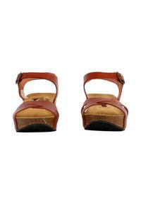 Sandalias de cuero marrón con suela intermedia de corcho, tira del tobillo ajustable y diseño frontal cruzado. Suela plana de goma texturizada que ofrece agarre.
