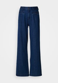 Τζιν παντελόνι με φαρδύ πόδι σε σκούρο μπλε τζιν ύφασμα. Διαθέτει εμπρόσθιο κλείσιμο με κουμπί και φερμουάρ, δύο μπροστινές τσέπες και δύο πίσω τσέπες. Ομαλή υφή χωρίς σχέδια.