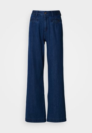 Τζιν παντελόνι με φαρδύ πόδι σε σκούρο μπλε τζιν ύφασμα. Διαθέτει εμπρόσθιο κλείσιμο με κουμπί και φερμουάρ, δύο μπροστινές τσέπες και δύο πίσω τσέπες. Ομαλή υφή χωρίς σχέδια.