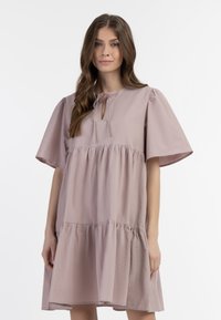 Lys mauve kjole lavet af blødt stof, med korte pufærmer, en rund hals med en nøglehulssløjfe, og en lagdelt flæsekant.