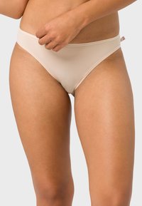 Beige nahtlose Panties mit einem niedrigen Bund, glatter Textur und subtilen elastischen Taillenbund, versehen mit einem kleinen Logo-Akzent.