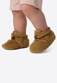 Pruunid fliisist pahkluu saapad pehme ja tekstuuriga pinnaga. Varustatud takjakinnitusrihma ja ümarate varvastega. Sobivad imikutele.