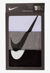 Τρία βρεφικά μπλουζάκια σε πακέτο: ένα λευκό, ένα γκρι και ένα μαύρο. Κάθε ένα έχει ένα εμφανές μαύρο λογότυπο Nike. Συσκευασμένα σε μαύρο κουτί.