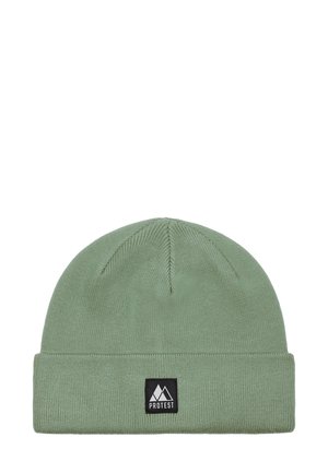 Green knit beanie with cuffed design, featuring a black rectangular brand label with a triangle logo on the front. Soft texture.