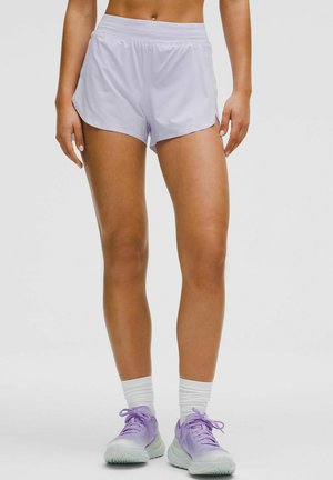 Liliowe spodenki sportowe z wygodnym pasem, bocznymi rozcięciami dla większej swobody ruchów oraz lekką teksturą. Połączone z pastelowymi fioletowymi trampkami.