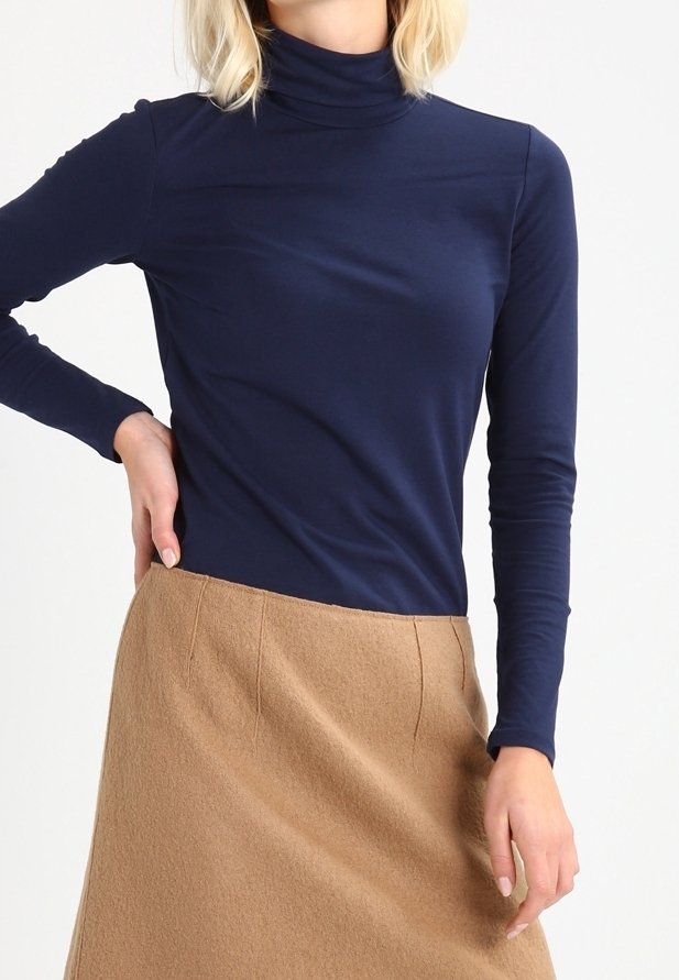 Granatowy golf wykonany z gładkiego materiału, zestawiony z camelową spódnicą do kolan o miękkiej teksturze i wyrazistym kroju.