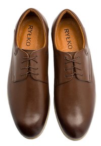 Barna bőr dresszcipő sima felülettel, fűzős kialakítással és enyhe varrási részletekkel. Belül egy világosbarna, texturált talpbetét található.