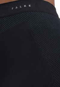 Black knitted fabric with subtle dark blue stripes. Features a logo "FALKE" on the waistband. Smooth texture, form-fitting design.
