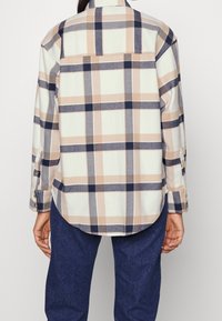 Geruite overhemd in lichtcrème, beige en marineblauwe kleuren. Zachte stof, lange mouwen met knoopmanchetten en een afgeronde onderkant.