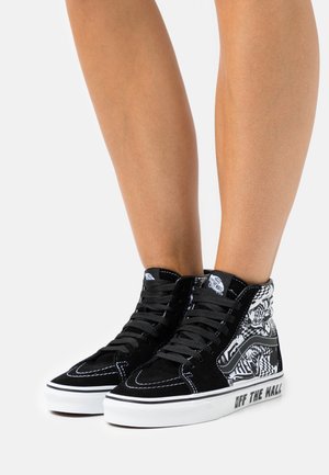Zapatillas altas de gamuza negra con cuello y suela blancos, que presentan un patrón gráfico monocromático y cordones negros. Logotipo "OFF THE WALL" en el lateral.