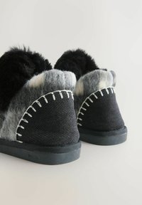 Black and gray felt slippers with soft black fur trim, featuring white stitching along the edges and rubber soles for traction.