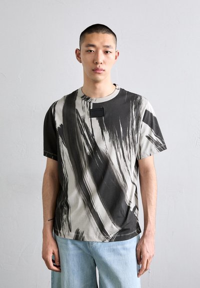 T-shirt a maniche corte astratto striato in bianco e grigio, materiale di cotone, scollatura rotonda, design aderente con un piccolo etichetta sul petto.