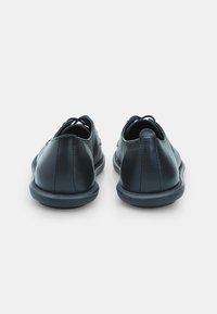 Sorte lædersko med lav profil, glat tekstur, rund tå og minimal snøredetalje. Blød gummisål for komfort.