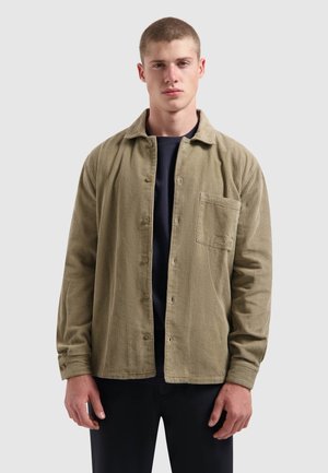 Olijfgroene corduroy shirt met een ontspannen pasvorm, knoopsluiting aan de voorkant en een borstzak. Voorzien van verticale ribbelstof en lange mouwen met knoopmanchetten.