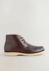 Dark brown leather ankle boot with three eyelets, rounded toe, and beige rubber sole on plain light background.