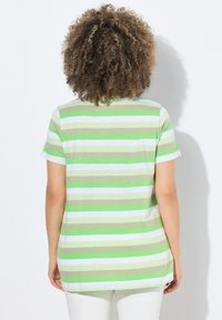 Lyhythihainen t-paita vihreän ja valkoisen raidallisen kuosin kanssa, valmistettu pehmeästä kankaasta. Omistaa pyöreän kaula-aukon ja rennon istuvuuden, jossa on hieman pidempi takapuoli.