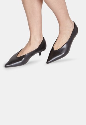 Décolleté nere in pelle con punta a punta, tacco kitten basso e cutout laterali, caratterizzate da una texture liscia e una silhouette elegante.