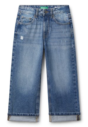 Jean en denim bleu avec des poignets retroussés, légers effets usés sur les cuisses, style à cinq poches, et une fermeture à bouton avec une étiquette verte à la taille.