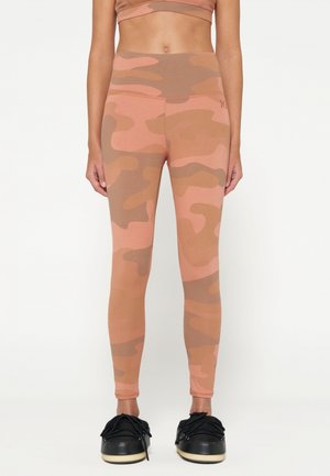 Legginsy w kamuflażu w odcieniach różu i brązu; dopasowany krój z wysokim stanem; gładka textura; połączone z czarnymi sneakerami.