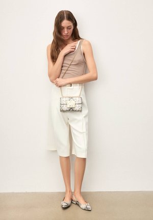 Valged lühikesed püksid ja beež top, mida täiendab väike maduprintidega käekott ja sobivad madalad kingad kettidega. Lihtne ja kaasaegne disain.