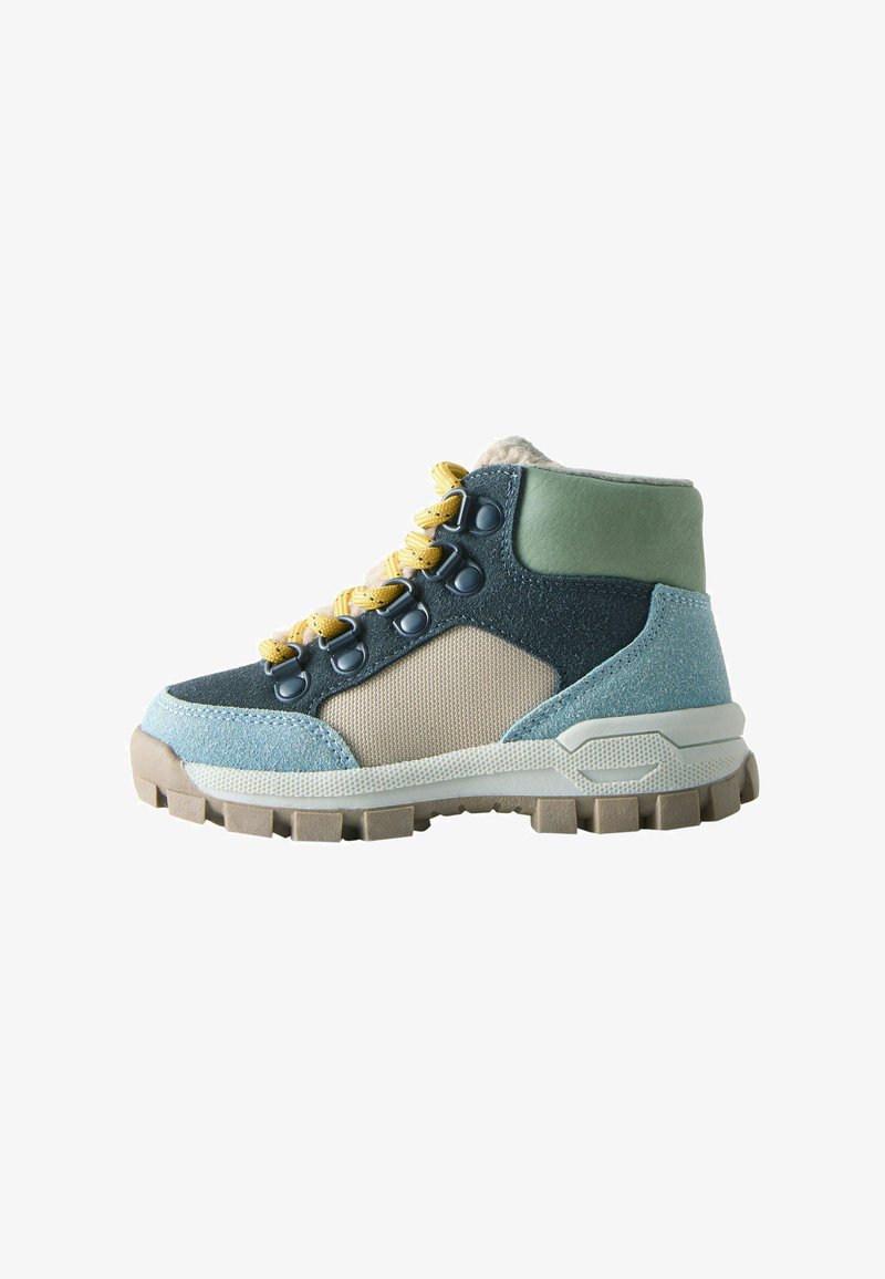 High-top hiking boots featuring a mix of blue, beige, and green materials, with textured fabric, yellow laces, and a rugged sole design.