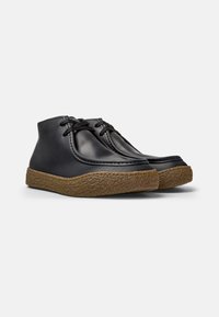 Schwarze Leder-Ankle Boots mit abgerundeter Spitze, gestickten Details und einer strukturierten braunen Gummisohle. Ausgestattet mit Schnürverschluss.