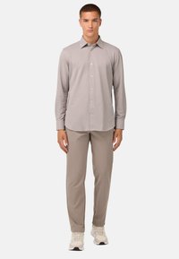 Camisa de botones de manga larga en gris claro, combinada con pantalones beige y zapatillas crema. Tejido suave; cuello estándar; silueta ajustada.