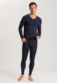 Haut thermique à manches longues bleu marine avec un col en V, associé à un legging thermique ajusté. Les deux sont fabriqués dans un matériau lisse et extensible.