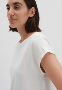 Maglietta bianca a maniche corte con vestibilità rilassata. Tessuto morbido e scollatura rotonda. Design semplice senza motivi o dettagli visibili.
