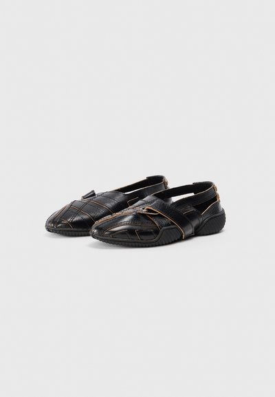 Svarta slip-on skor med en texturerad läderövre del, med tvärs överliggende remmar och en gummisula. Inkluderar kontrasterande sömdetaljer.
