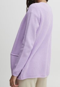 Lavendelstickad cardigan med en strukturerad yta, med avslappnad passform, långa ärmar och sidfickor för praktisk användning.