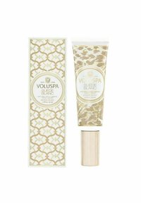 Voluspa Suede Blanc håndcreme i en guld- og hvidtube med en blank hætte, ved siden af en mønstret æske med indviklede designs.