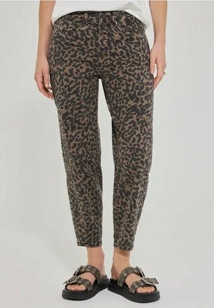 Kvinde iført højtaljede leopardprintbukser med opkørte kanter og sorte sandaler med sølv spænder og øjne.