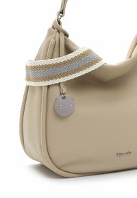 Beige leather handbag with a textured surface, featuring a woven strap in cream, gray, and brown, and a silver logo pendant.