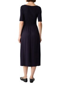 Abito midi blu navy con busto a coste, maniche corte e gonna fluida. Tessuto liscio, vita elastica e scarpe nere piatte.