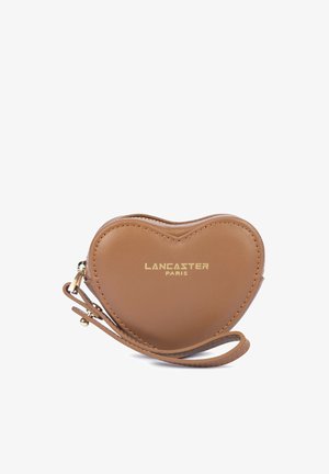 Pochette bracelet en cuir marron en forme de cœur avec logo doré "Lancaster Paris" et fermeture éclair sur fond blanc.