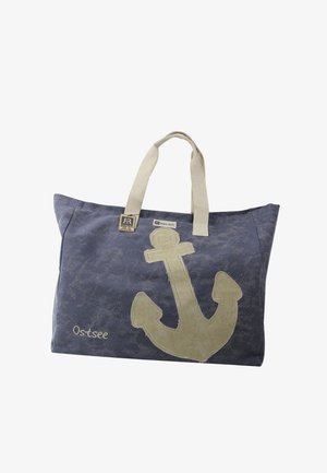 Blauwe canvas draagtas met beige ankerontwerp, beige handvatten en "Ostsee" geborduurd in de linkerbenedenhoek.