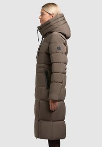 Lang, gewatteerde winterjas in bruin met een hoge kraag, ritszakken aan de zijkant en een verstelbare capuchon. Glad materiaal met een gewatteerde textuur.