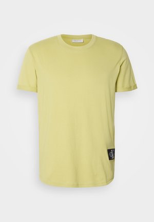 Lime green cotton t-shirt with a crew neck, short sleeves, and a black CK logo patch on the left side near the hem.