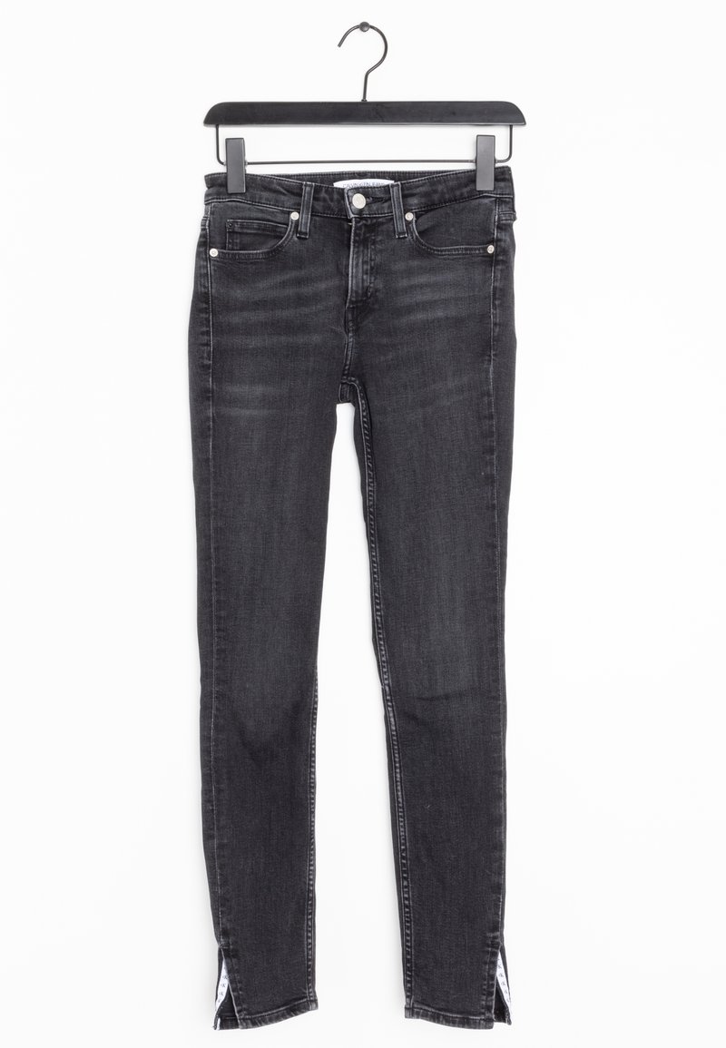 Jeans skinny de mezclilla negra con una cintura de media altura, que cuentan con aberturas laterales en el dobladillo y un estilo clásico de cinco bolsillos. Textura suave.